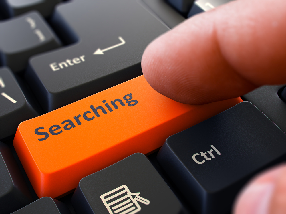 Searching Button. Male Finger Clicks on Orange Button on Black Keyboard. Closeup View. Blurred Background.