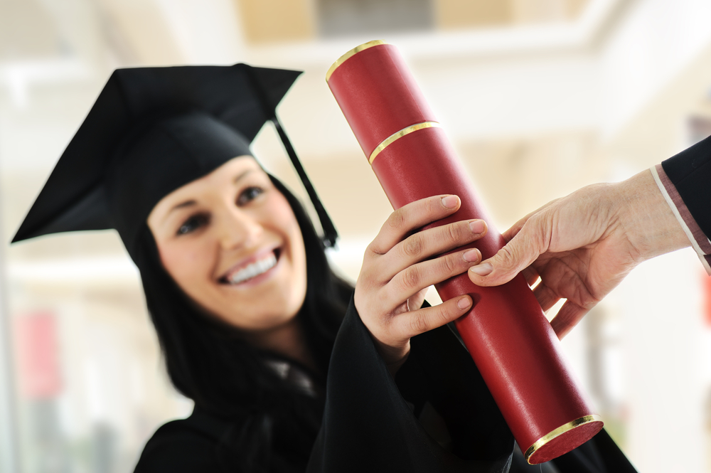 Young female graduating and receiving diploma at university